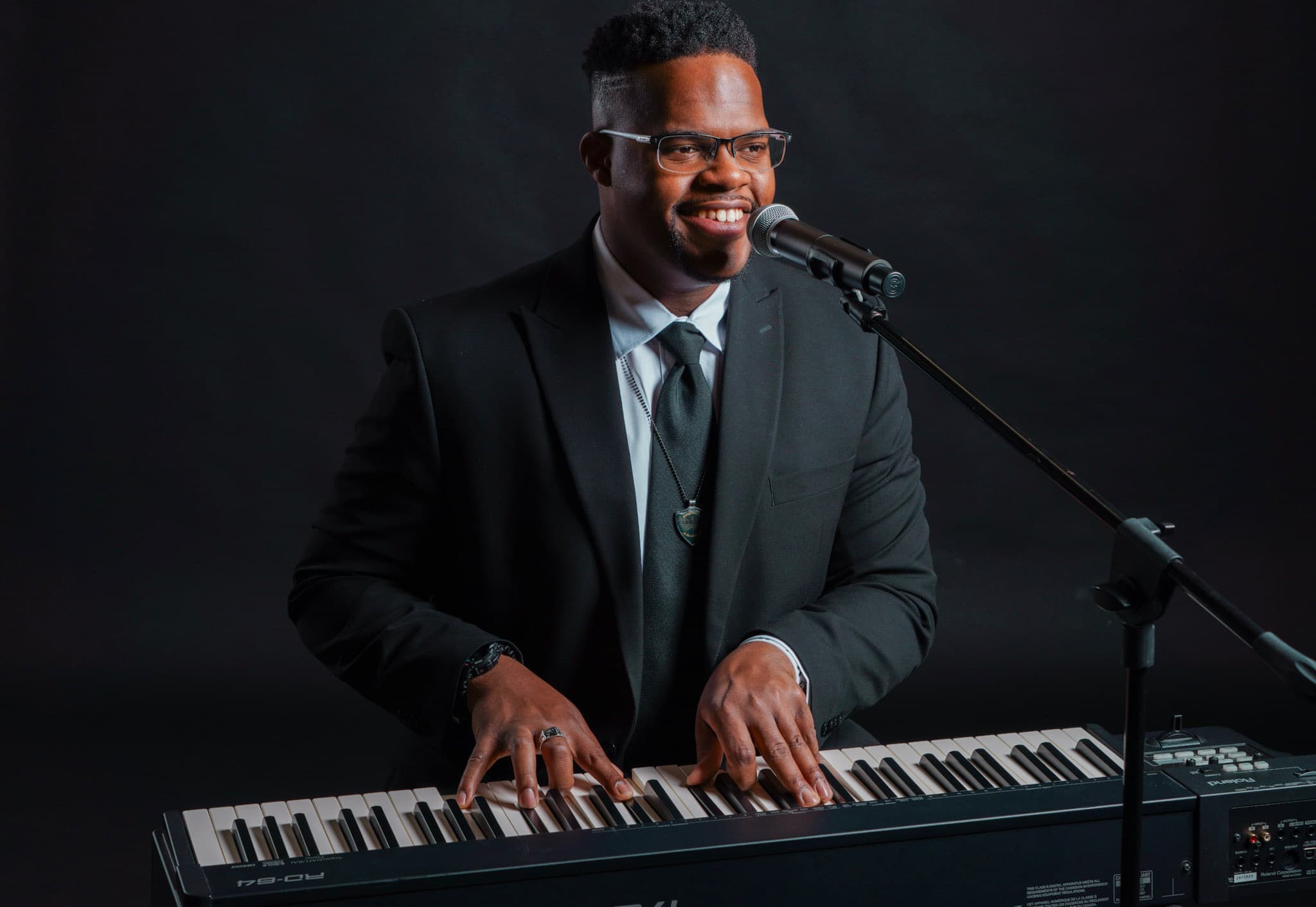 JKelly Music smiling while playing keyboard at a microphone