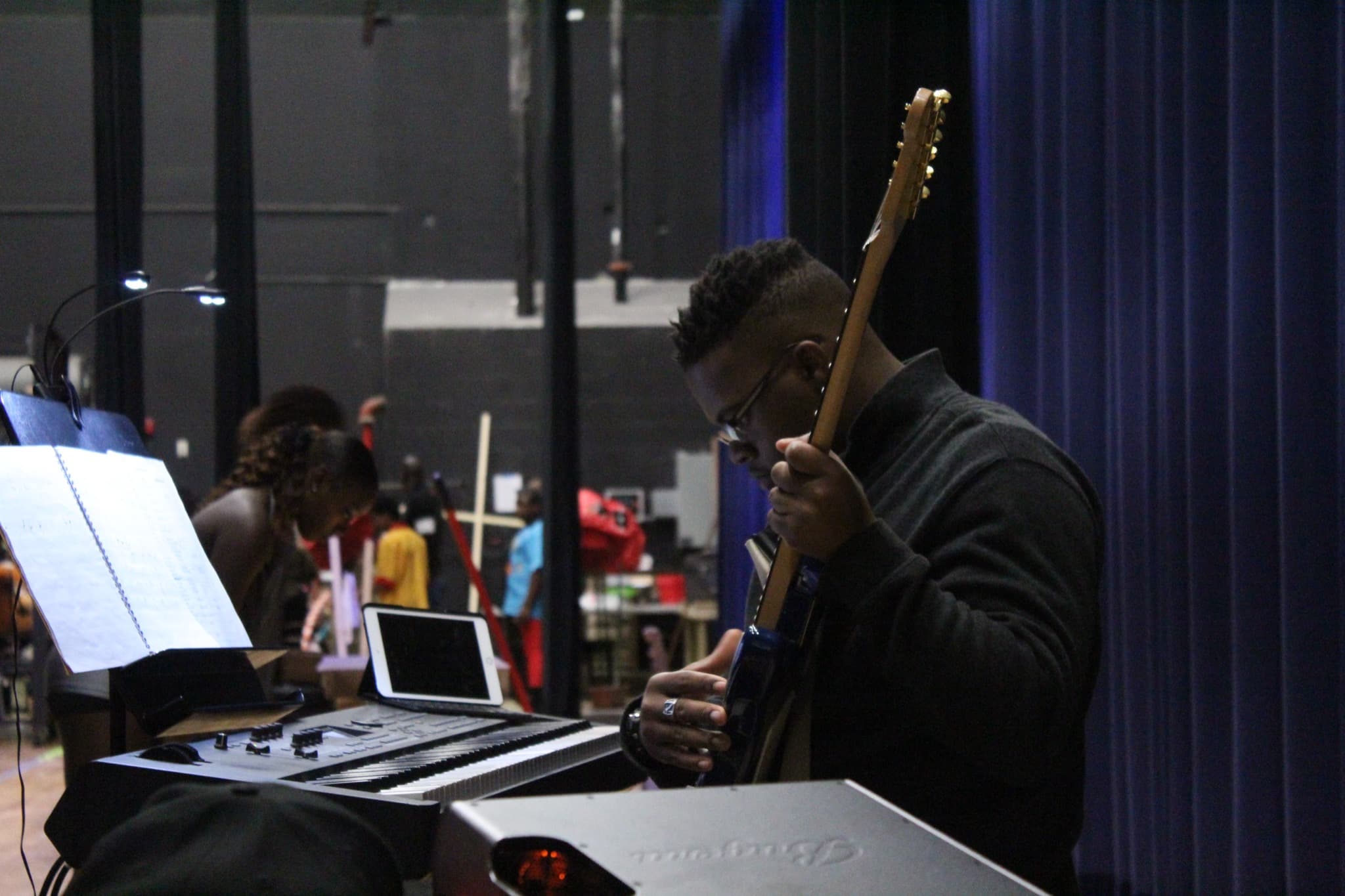 JKelly Music playing guitar at a rehearsal with sheet music and keyboard
